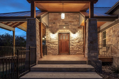 Photo of a mid-sized country one-storey brown house exterior in Austin with stone veneer, a hip roof and a metal roof.