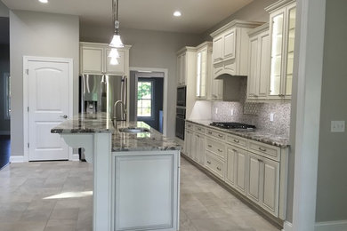 Example of a mid-sized transitional galley ceramic tile eat-in kitchen design in Other with a double-bowl sink, raised-panel cabinets, white cabinets, granite countertops, gray backsplash, matchstick tile backsplash, stainless steel appliances and an island
