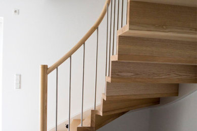 Diseño de escalera curva contemporánea extra grande con escalones de madera, contrahuellas de madera y barandilla de varios materiales