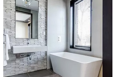 Modelo de cuarto de baño principal minimalista grande con bañera exenta, paredes blancas, suelo de baldosas de porcelana, lavabo suspendido y suelo gris