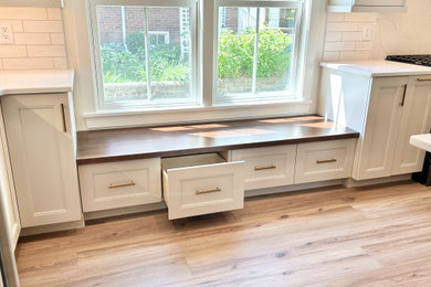 Inspiration for a large transitional u-shaped light wood floor open concept kitchen remodel in Other with an undermount sink, flat-panel cabinets, white cabinets, quartz countertops, white backsplash, ceramic backsplash, black appliances, an island and white countertops
