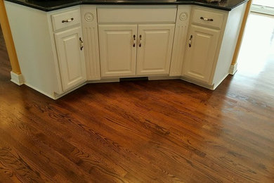 Mid-sized transitional kitchen in Omaha with raised-panel cabinets, white cabinets, medium hardwood floors, with island and brown floor.