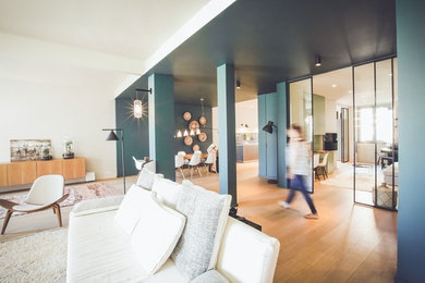 Réalisation d'une grande salle de séjour design ouverte avec une bibliothèque ou un coin lecture, un mur blanc, parquet foncé, aucune cheminée et un sol marron.