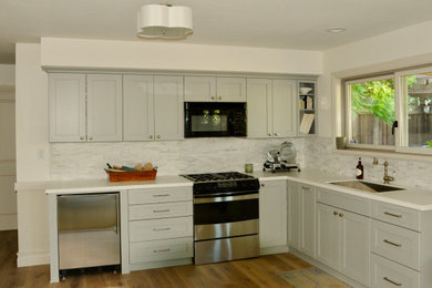 Example of a transitional kitchen design in San Francisco with a single-bowl sink, shaker cabinets, solid surface countertops, gray backsplash, marble backsplash, stainless steel appliances, no island and white countertops