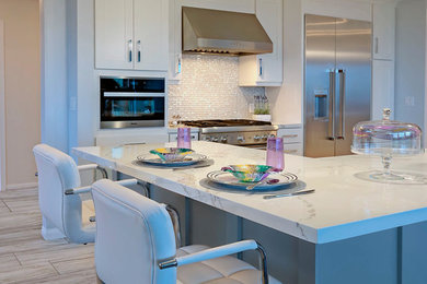 Example of a mid-sized minimalist u-shaped porcelain tile and gray floor open concept kitchen design in San Diego with a farmhouse sink, shaker cabinets, gray cabinets, quartz countertops, glass tile backsplash, stainless steel appliances, an island and white countertops