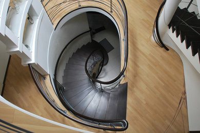 Стильный дизайн: большая изогнутая металлическая лестница в современном стиле с крашенными деревянными ступенями - последний тренд