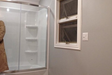 Mid-sized elegant 3/4 ceramic tile ceramic tile drop-in bathtub photo in New York with white cabinets, solid surface countertops, a one-piece toilet and gray walls