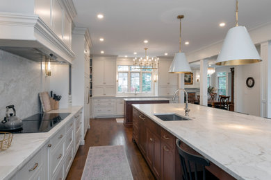 Eat-in kitchen - huge transitional galley medium tone wood floor and brown floor eat-in kitchen idea in Cleveland with an undermount sink, beaded inset cabinets, white cabinets, quartzite countertops, white backsplash, stone slab backsplash, paneled appliances, two islands and white countertops