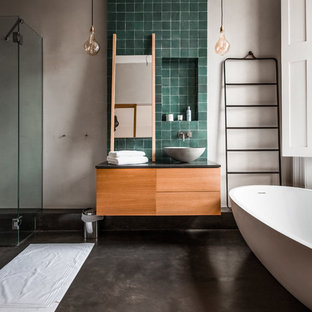 Inspiration pour une grande salle d'eau design avec une baignoire indépendante, des carreaux en terre cuite, un mur beige, un plan de toilette en bois, un placard à porte plane, béton au sol, une vasque, un sol gris, une cabine de douche à porte battante, des portes de placard en bois brun et un carrelage vert.