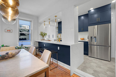 Example of a large minimalist galley ceramic tile and gray floor eat-in kitchen design in New York with an undermount sink, shaker cabinets, blue cabinets, quartz countertops, white backsplash, ceramic backsplash, stainless steel appliances, an island and white countertops