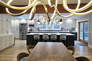Eat-in kitchen - mid-sized craftsman light wood floor and beige floor eat-in kitchen idea in New York with a single-bowl sink, shaker cabinets, white cabinets, quartz countertops, blue backsplash, glass sheet backsplash, stainless steel appliances, an island and white countertops