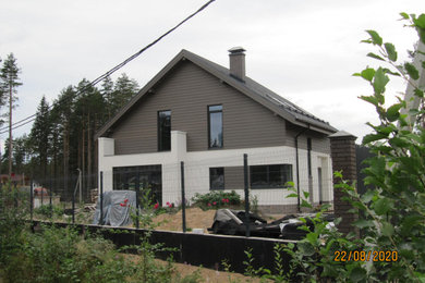 На фото: двухэтажный, серый частный загородный дом среднего размера в скандинавском стиле с двускатной крышей и крышей из гибкой черепицы