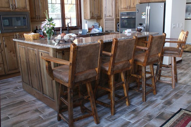 Mountain style dark wood floor and gray floor enclosed kitchen photo in Other with raised-panel cabinets, dark wood cabinets, granite countertops, stainless steel appliances and an island