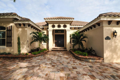 Large tuscan beige one-story stucco house exterior photo with a hip roof and a shingle roof