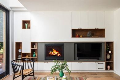 Design ideas for a contemporary open concept family room in New York with light hardwood floors, a standard fireplace and a built-in media wall.