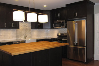 Eat-in kitchen - mid-sized transitional l-shaped medium tone wood floor eat-in kitchen idea in Philadelphia with a farmhouse sink, beaded inset cabinets, dark wood cabinets, granite countertops, white backsplash, subway tile backsplash, stainless steel appliances and an island