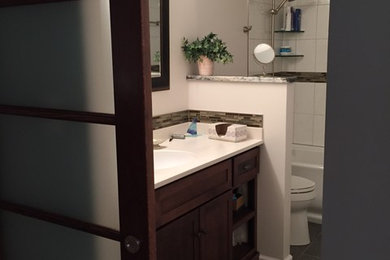 Small elegant master white tile and porcelain tile ceramic tile bathroom photo in New York with an integrated sink, dark wood cabinets, solid surface countertops, a one-piece toilet, white walls and shaker cabinets