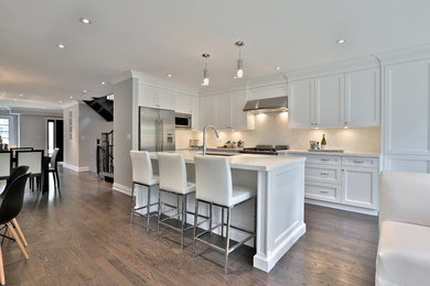 Inspiration for a large contemporary l-shaped medium tone wood floor and brown floor open concept kitchen remodel in Toronto with an undermount sink, shaker cabinets, white cabinets, marble countertops, white backsplash, stainless steel appliances and an island