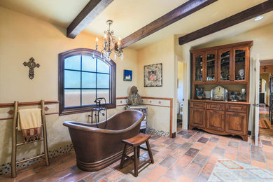 Design ideas for a large mediterranean master bathroom in Los Angeles with raised-panel cabinets, dark wood cabinets, a freestanding tub, a corner shower, beige tile, ceramic tile, beige walls, terra-cotta floors, an undermount sink, marble benchtops, multi-coloured floor and a hinged shower door.