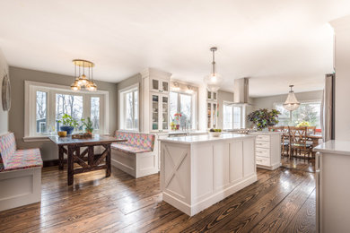 Example of a mid-sized country u-shaped vinyl floor and brown floor eat-in kitchen design in Other with a farmhouse sink, glass-front cabinets, white cabinets, quartz countertops, stainless steel appliances, an island and white countertops