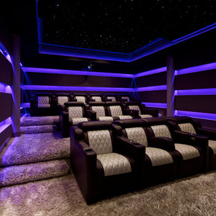 Cette image montre une salle de cinéma minimaliste de taille moyenne et fermée avec moquette, un sol beige, un mur violet et un téléviseur encastré.