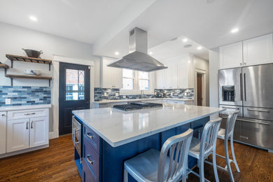 Kitchen - traditional painted wood floor and brown floor kitchen idea in DC Metro with an undermount sink, shaker cabinets, quartz countertops, blue backsplash, glass tile backsplash, stainless steel appliances, an island and white countertops