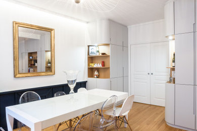 This is an example of a mid-sized contemporary dining room in Paris with white walls, light hardwood floors and no fireplace.