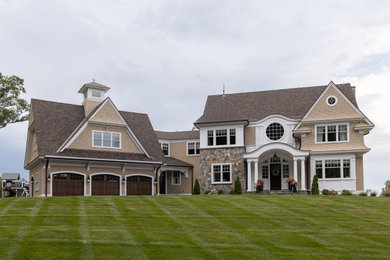 Inspiration for a large timeless beige three-story mixed siding and shingle exterior home remodel in Bridgeport with a brown roof and a mixed material roof