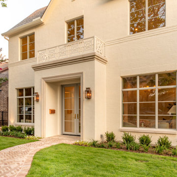 Front entry glowing at dusk with copper lanterns and balcony railin