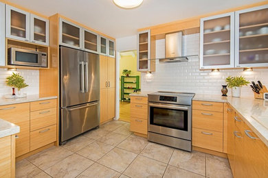Inspiration for a mid-sized contemporary kitchen pantry in Hawaii with a drop-in sink, flat-panel cabinets, light wood cabinets, quartz benchtops, white splashback, subway tile splashback, stainless steel appliances, ceramic floors and beige floor.