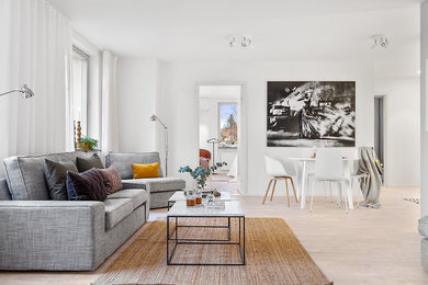 Small scandinavian formal open concept living room in Stockholm with white walls, no fireplace, no tv and light hardwood floors.