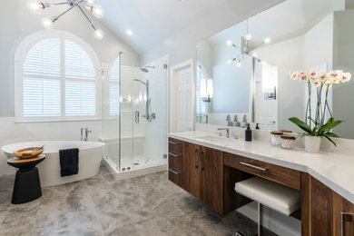 Photo of a large contemporary master bathroom in Houston with flat-panel cabinets, brown cabinets, a freestanding tub, a corner shower, a two-piece toilet, white tile, ceramic tile, grey walls, porcelain floors, an undermount sink, engineered quartz benchtops, grey floor, a hinged shower door and white benchtops.