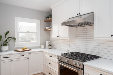 Example of a small transitional galley medium tone wood floor and brown floor enclosed kitchen design in Seattle with an undermount sink, recessed-panel cabinets, white cabinets, quartzite countertops, white backsplash, porcelain backsplash, stainless steel appliances, no island and white countertops