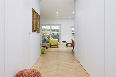 Inspiration for a contemporary entryway in Rome with white walls and light hardwood floors.