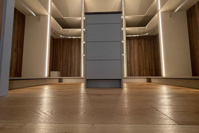 Medium sized contemporary gender neutral walk-in wardrobe in Sussex with open cabinets and feature lighting.