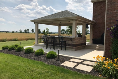 Large elegant backyard concrete patio kitchen photo in Other with a gazebo
