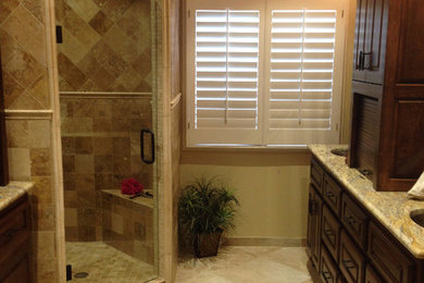 Large elegant master brown tile and stone tile travertine floor corner shower photo in Dallas with an undermount sink, raised-panel cabinets, dark wood cabinets, granite countertops, a two-piece toilet and beige walls
