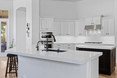 Inspiration for a large modern u-shaped eat-in kitchen remodel in Phoenix with an undermount sink, shaker cabinets, white cabinets, quartz countertops, white backsplash, ceramic backsplash, stainless steel appliances, two islands and white countertops