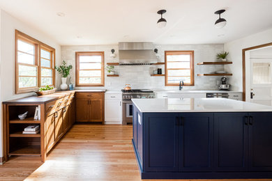Inspiration for a cottage medium tone wood floor eat-in kitchen remodel in Portland with recessed-panel cabinets, ceramic backsplash, stainless steel appliances, an island and white countertops