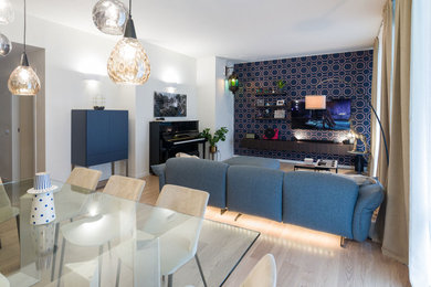 Imagen de salón minimalista sin chimenea con paredes azules, suelo de madera clara y televisor colgado en la pared