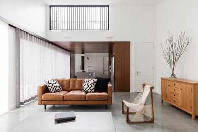 Contemporary open concept living room in Sydney with white walls and concrete floors.