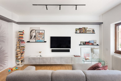 Foto de salón abierto contemporáneo de tamaño medio con paredes blancas, suelo de madera clara, televisor colgado en la pared, suelo marrón y papel pintado
