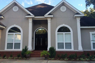 Large traditional beige two-story concrete exterior home idea in Miami with a clipped gable roof