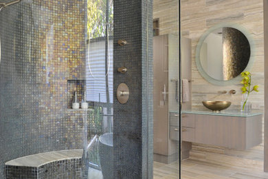 Example of a huge trendy stone tile and gray tile travertine floor bathroom design in Dallas with a vessel sink, flat-panel cabinets, light wood cabinets, glass countertops and gray walls