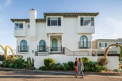 Mediterranean white two-story house exterior idea in Santa Barbara with a tile roof and a red roof