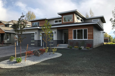 Photo of a mid-sized arts and crafts two-storey grey house exterior in Other with wood siding and a shingle roof.