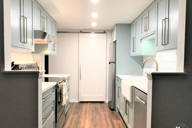 Small transitional galley vinyl floor and brown floor kitchen photo in Other with a farmhouse sink, shaker cabinets, blue cabinets, quartz countertops, white backsplash, subway tile backsplash, stainless steel appliances, no island and white countertops