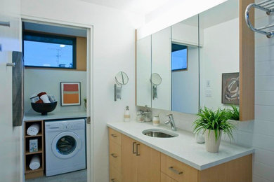 Inspiration for a transitional white tile and ceramic tile bathroom/laundry room remodel in Vancouver with flat-panel cabinets, medium tone wood cabinets, granite countertops, white walls and a drop-in sink