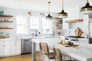 Inspiration for a large country l-shaped kitchen in Boston with a farmhouse sink, shaker cabinets, white cabinets, marble benchtops, white splashback, subway tile splashback, stainless steel appliances, medium hardwood floors and with island.