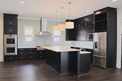 Inspiration for a large modern l-shaped medium tone wood floor and brown floor eat-in kitchen remodel in Other with a farmhouse sink, shaker cabinets, dark wood cabinets, quartz countertops, green backsplash, glass tile backsplash, stainless steel appliances and an island